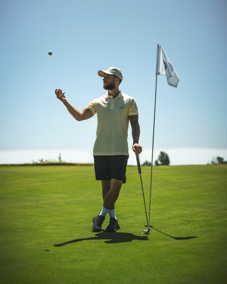 A golfer lines up a shot on a green fairway, carefully focusing on a small target in the distance.