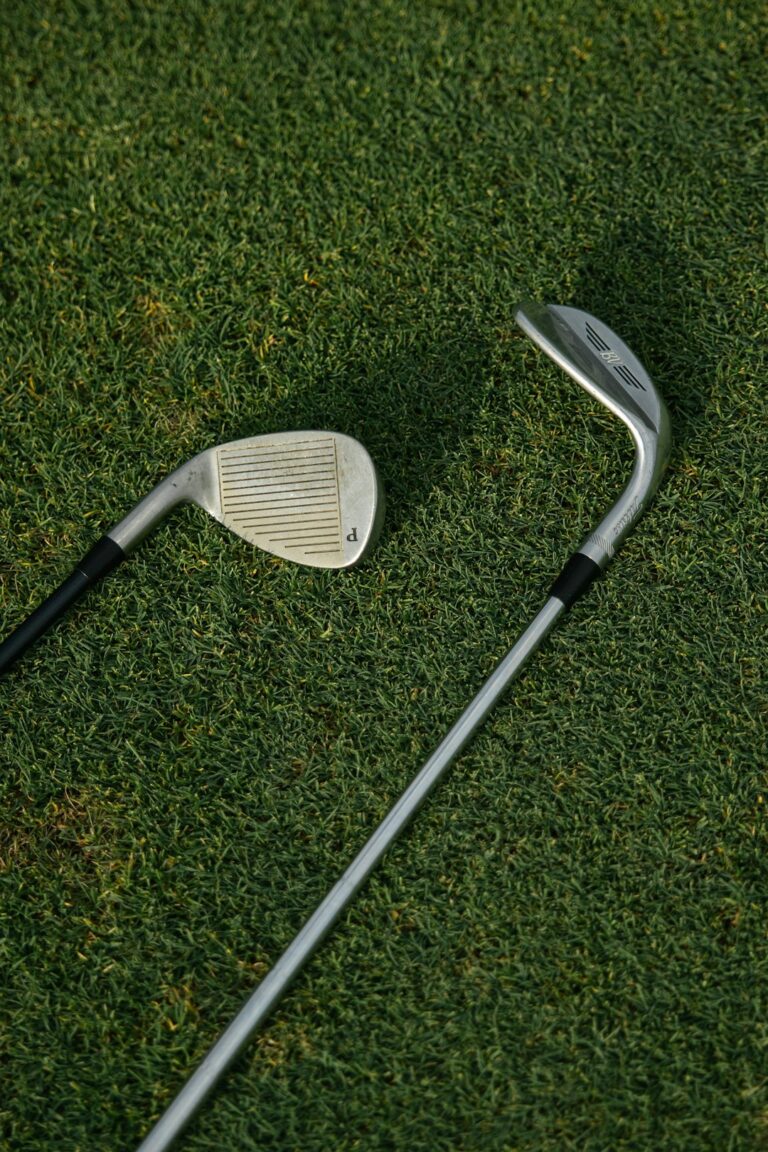 A pair of hands inspecting the grip of a golf club on a green grass background outdoors.