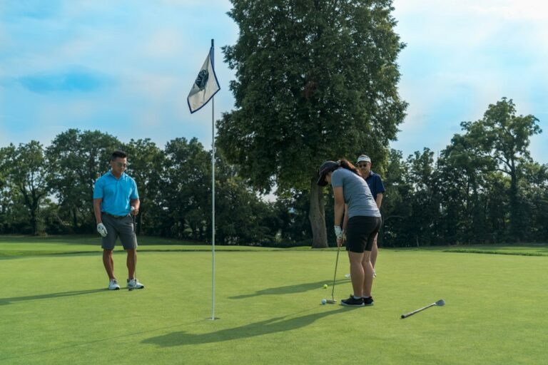 Golfers practicing swings together while an instructor reviews ball-flight data on a simulator screen.
